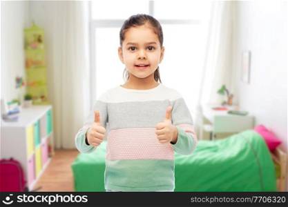 childhood, fashion and people concept - happy smiling girl showing thumbs up over white background. happy smiling girl showing thumbs up
