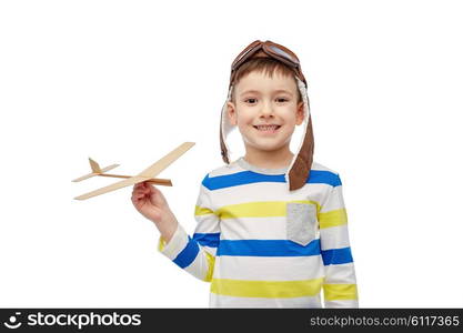 childhood, fashion and people concept - happy smiling little boy in aviator hat playing with wooden airplane