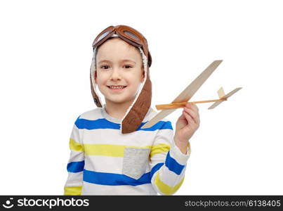 childhood, fashion and people concept - happy smiling little boy in aviator hat playing with wooden airplane