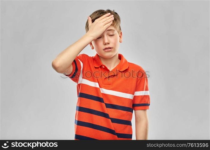 childhood, fashion and people concept - portrait of boy in red polo t-shirt having headache over grey background. boy in red polo t-shirt having headache