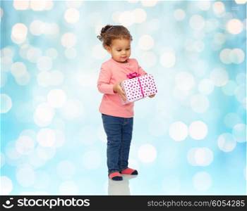 childhood, fashion, birthday, holidays and people concept - beautiful little african american baby girl with gift box over blue lights background