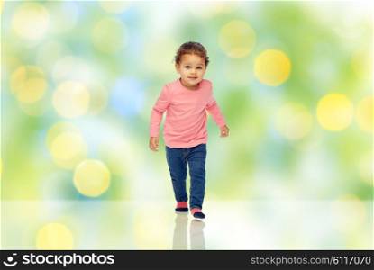 childhood, fashion, clothing and people concept - beautiful little african american baby girl walking over green summer light background