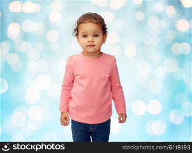 childhood, fashion, clothing and people concept - beautiful little african american baby girl portrait over blue holidays lights background