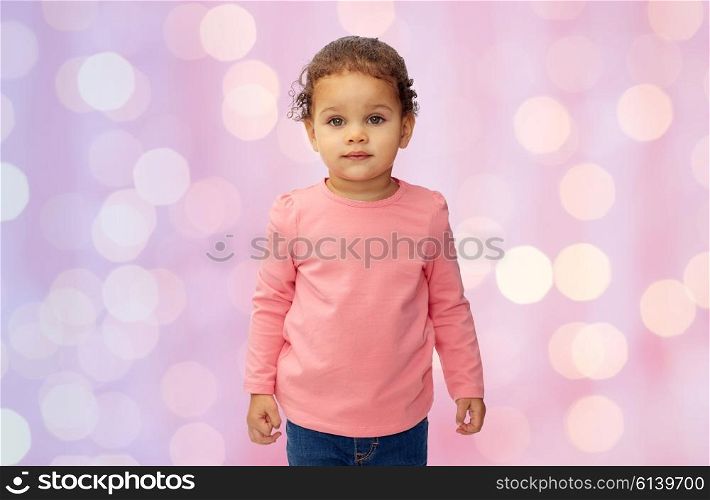 childhood, fashion, clothing and people concept - beautiful little african american baby girl portrait over pink holidays lights background