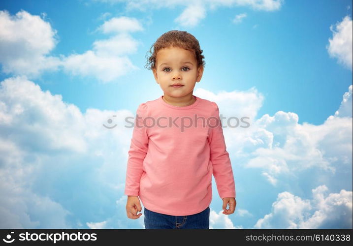 childhood, fashion, clothing and people concept - beautiful little african american baby girl portrait over blue sky and clouds background