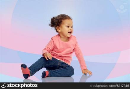 childhood, fashion, clothing and people concept - smiling beautiful african american little baby girl sitting on floor over pink violet background