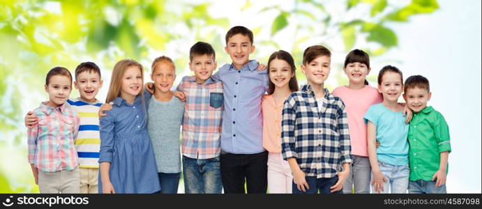 childhood, fashion, friendship and people concept - group of happy smiling children hugging over green natural background