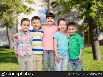 childhood, fashion, friendship and people concept - group of happy smiling little children hugging over summer campus background