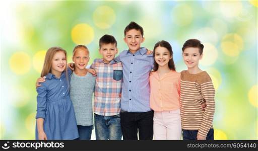 childhood, fashion, friendship and people concept - happy smiling children hugging over green lights background