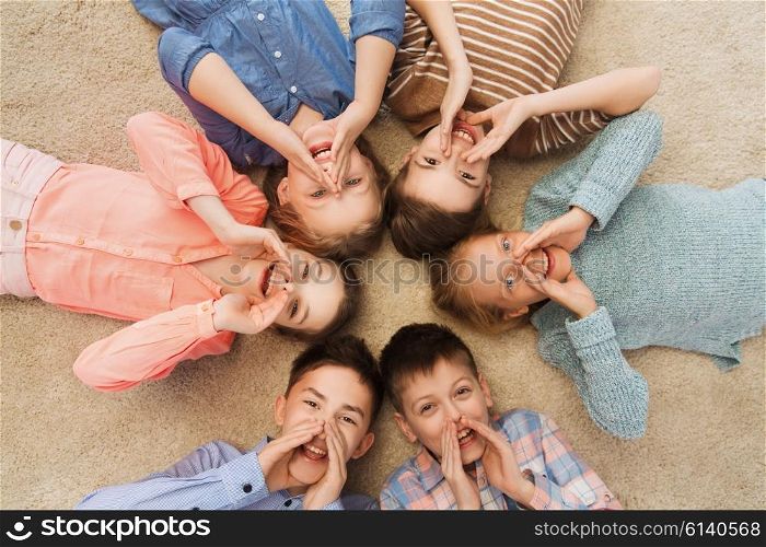 childhood, fashion, friendship and people concept - happy smiling children lying on floor in circle and calling or shouting
