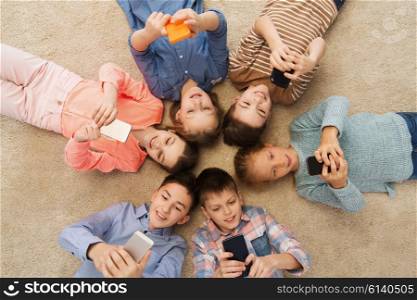 childhood, fashion, friendship and people concept - happy smiling children lying on floor in circle