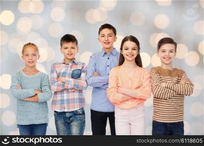 childhood, fashion, friendship and people concept - happy smiling children over holidays lights background