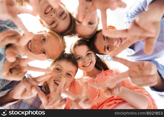 childhood, fashion, friendship and people concept - happy smiling children showing peace hand sign and standing in circle