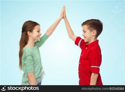 childhood, fashion, gesture and people concept - happy smiling boy and girl making high five over blue background