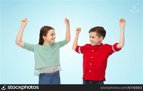 childhood, fashion, gesture and people concept - happy smiling boy and girl raising fists and celebrating victory over blue background