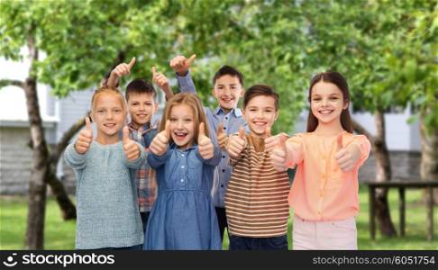 childhood, fashion, gesture and people concept - happy smiling children showing thumbs up over private house backyard background