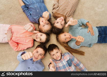 childhood, fashion, gesture and people concept - happy smiling children showing thumbs up and lying on floor in circle