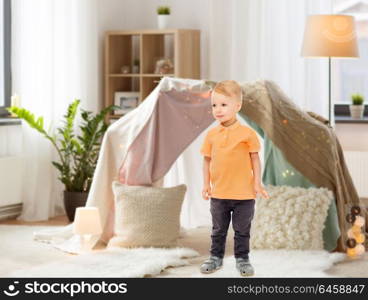 childhood, fashion, joy and people concept - happy little boy at home over kids room and tepee background. happy little boy at home
