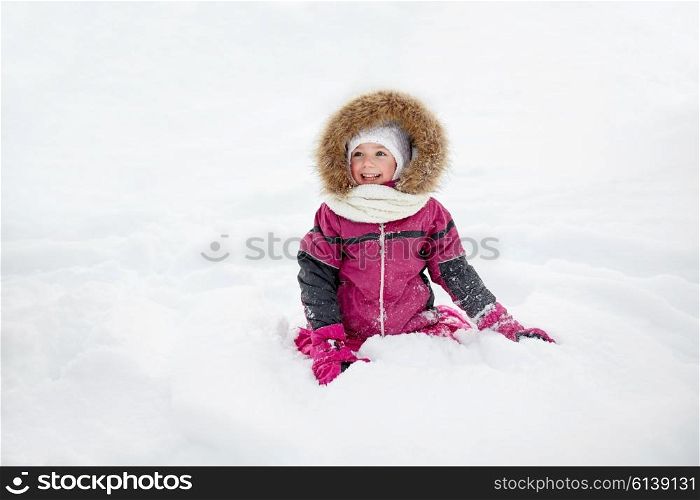 childhood, fashion, season and people concept - face of happy little kid or girl in winter clothes on snow