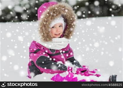 childhood, fashion, season and people concept - happy little kid in winter clothes playing with snow outdoors