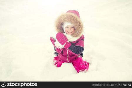 childhood, fashion, season and people concept - happy little kid or girl in winter clothes playing with snow. f happy little child or girl with snow in winter