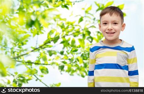 childhood, fashion, summer and people concept - happy smiling little boy over green natural background