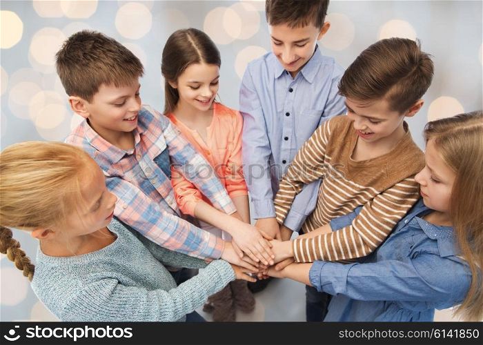 childhood, friendship and people concept - happy children with hands on top over holidays lights background
