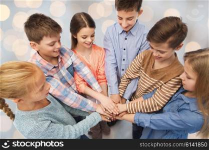 childhood, friendship and people concept - happy children with hands on top over holidays lights background