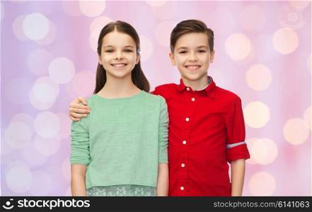 childhood, friendship and people concept - happy smiling boy and girl hugging over pink holidays lights background