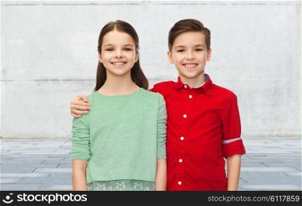 childhood, friendship and people concept - happy smiling boy and girl hugging over urban street background