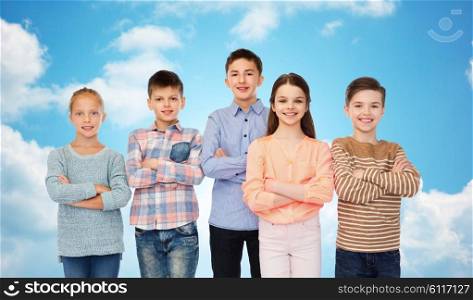 childhood, friendship and people concept - happy smiling children over blue sky and clouds background