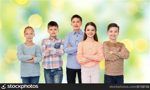 childhood, friendship and people concept - happy smiling children over green summer holidays lights background