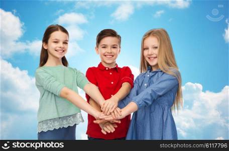 childhood, friendship and people concept - happy smiling children with hands on top over blue sky and clouds background