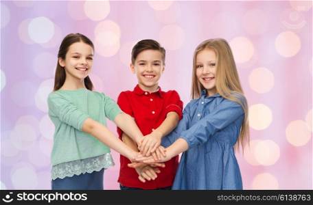 childhood, friendship, friendship and people concept - happy smiling children with hands on top over pink holidays lights background