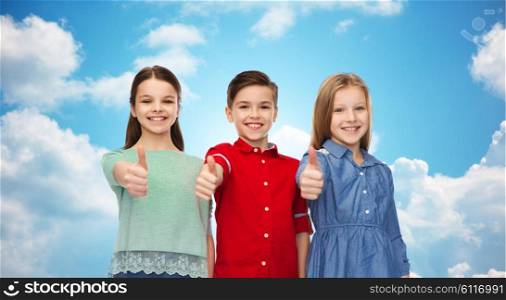 childhood, friendship, gesture and people concept - happy smiling children showing thumbs up over blue sky and clouds background