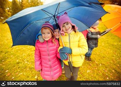childhood, friendship, season, weather and people concept - group of happy kids with umbrella in autumn park