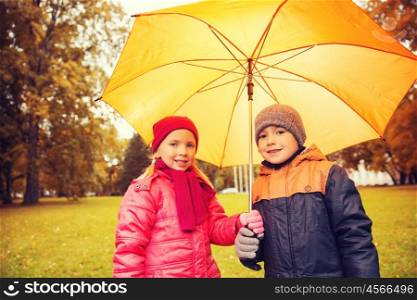 childhood, friendship, season, weather and people concept - happy little boy and girl with umbrella in autumn park. happy boy and girl with umbrella in autumn park