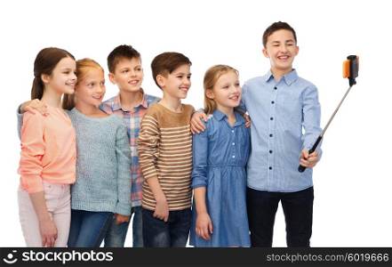 childhood, friendship, technology and people concept - happy children talking picture by smartphone on selfie stick