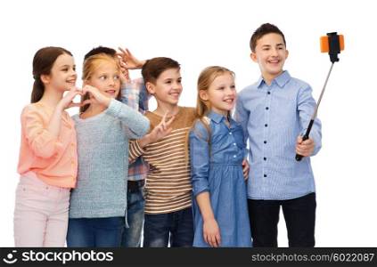childhood, friendship, technology and people concept - happy children talking picture by smartphone on selfie stick