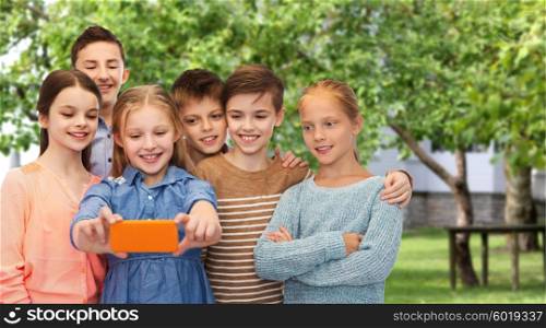 childhood, friendship, technology and people concept - happy children talking selfie by smartphone over private house backyard background
