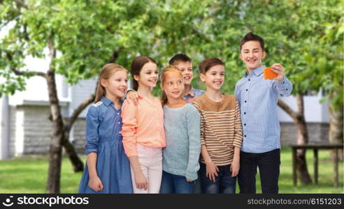 childhood, friendship, technology and people concept - happy children talking selfie by smartphone over private house backyard background