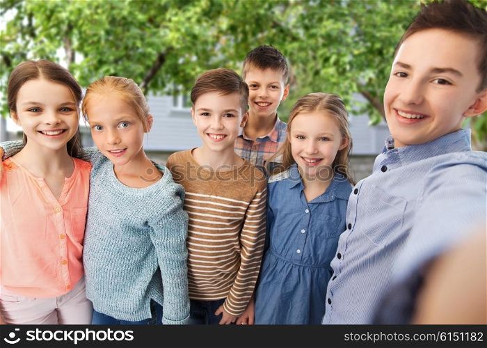 childhood, friendship, technology and people concept - happy children talking selfie over private house backyard background