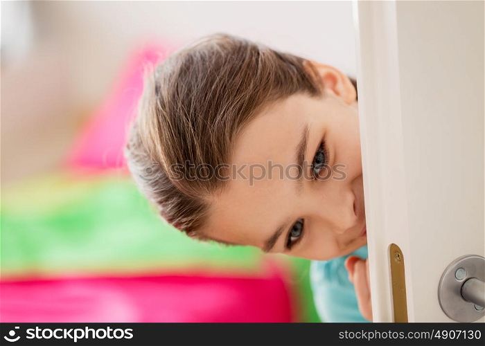 childhood, fun and people concept - happy smiling beautiful girl behind door at home. happy smiling beautiful girl behind door at home