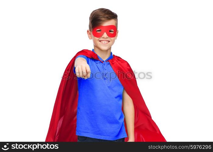 childhood, gesture, carnival costume and people concept - happy boy in red superhero cape and mask pointing finger to you
