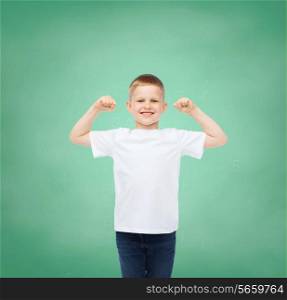 childhood, gesture, education, advertisement and people concept - smiling boy in white t-shirt with raised hands over green board background