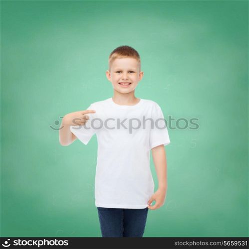 childhood, gesture, education and advertisement concept - smiling boy in t-shirt pointing his finger at himself over green board background