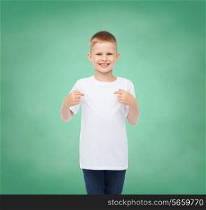 childhood, gesture, education and advertisement concept - smiling boy in t-shirt pointing his fingers at himself over green board background