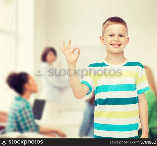 childhood, gesture, education and people concept - smiling little boy making ok gesture over group of students in classroom