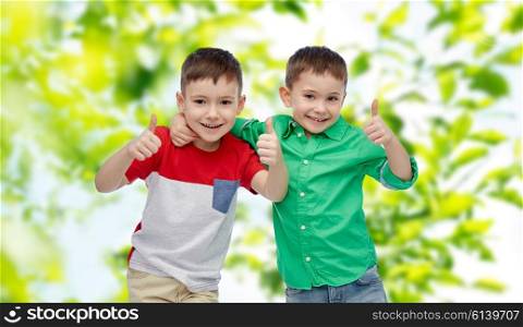 childhood, gesture, friendship, summer and people concept - happy smiling little boys showing thumbs up over green natural background