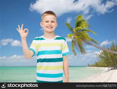 childhood, gesture, summer, travel and people concept - smiling little boy making ok sign over tropical beach background